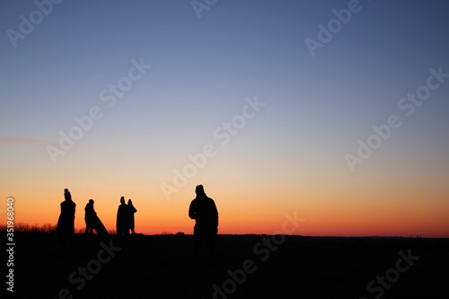 Sunrise silhouettes on hill 