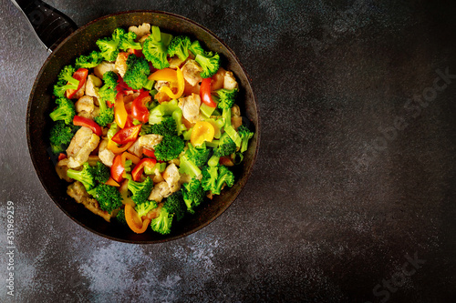 Asian stir-fry meat with paprika and broccoli in wok.