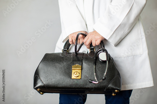 Female physician holding a black leather doctor's bag heading to the office to practice medicine photo