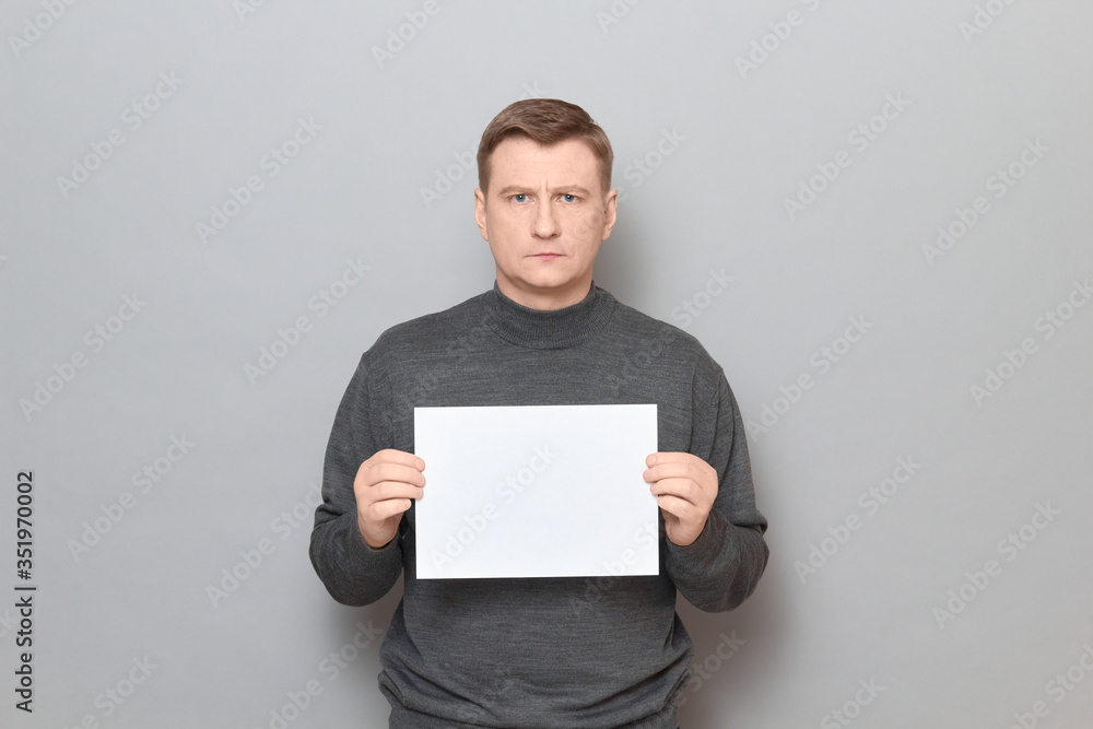 Portrait of serious man holding white blank paper sheet in hands Portrait of serious man holding white blank paper sheet in hands
