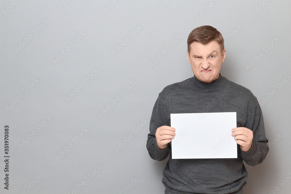 Portrait of angry man holding white blank paper sheet in hands Portrait of angry man holding white blank paper sheet in hands