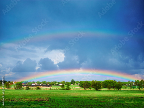 double rainbow after a thunderstorm over a green field