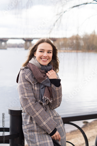 Smiling beautiful girl in a park in a fashionable coat. Checkered autumn coat