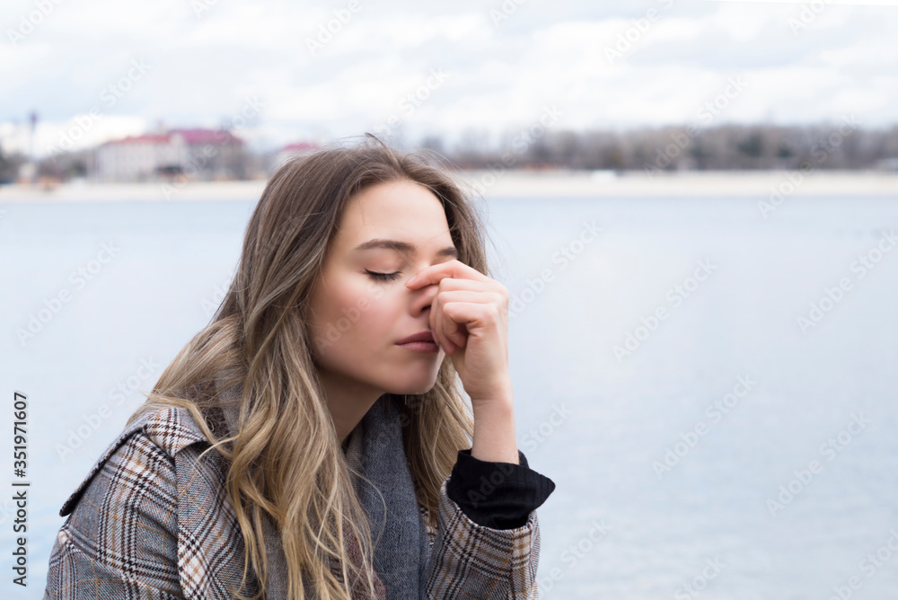 Smiling beautiful girl in a park in a fashionable coat. Checkered autumn coat