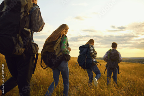 Group of friends trekking with backpacks walking in the forest . © Studio Romantic