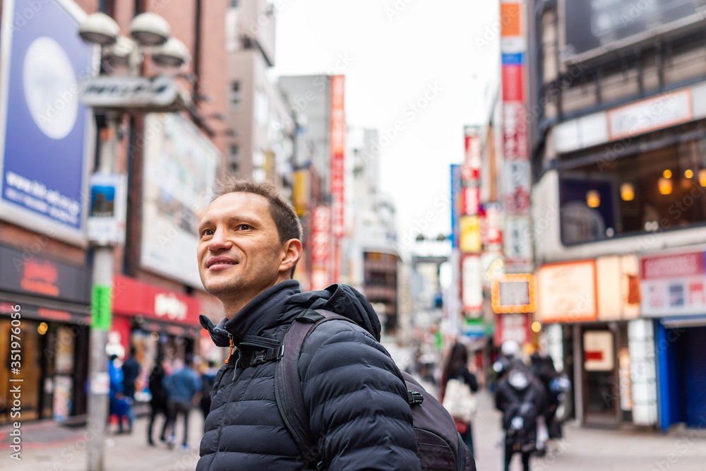 Tokyo, Japan Shibuya district with closeup of happy man tourist in famous Koen dori shopping street in downtown city with colorful architecture in bokeh background Tokyo, Japan Shibuya district with closeup of happy man tourist in famous Koen dori shopping street in downtown city with colorful architecture in bokeh background