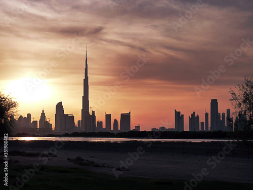 Sunset over the city near the Lake. Burj Khalifa and different buildings in sunset view. Travel by car in the United Arab Emirates. Image with selective focus, noise effect and toning.