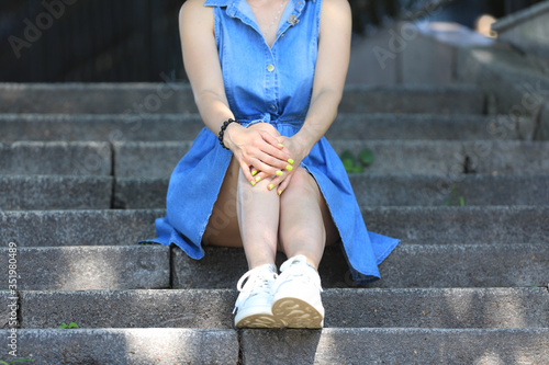 beautiful legs of a sitting girl in a blue denim skirt