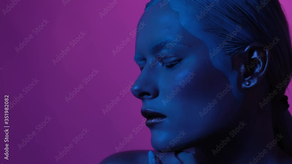 Beautiful young woman touches her lips and looks into camera. Game of purple and blue lights add some romantic mood. Prores 422 Beautiful young woman touches her lips and looks into camera. Game of purple and blue lights add some romantic mood. Prores 422