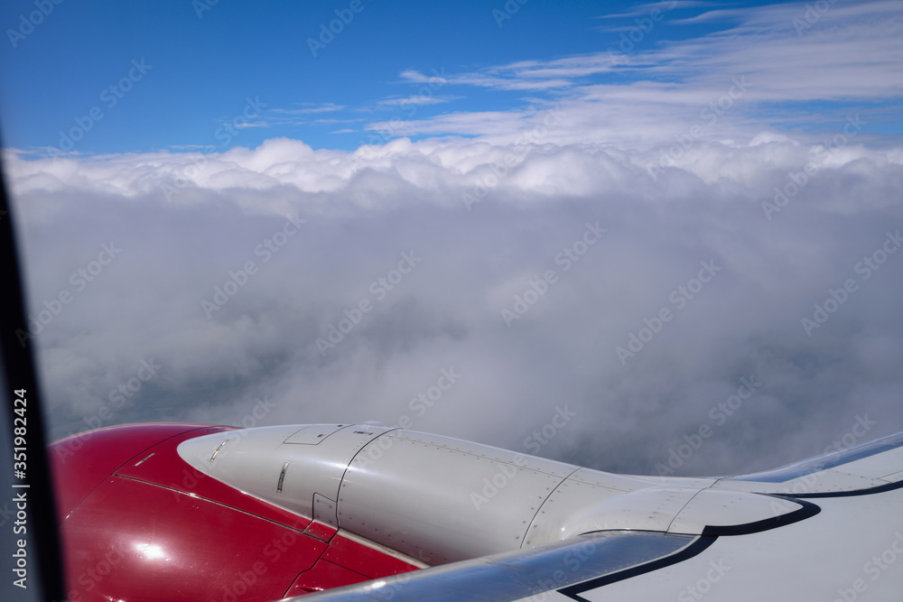 Airplane in flight. View from the window of an airplane over a blue sky, clouds, a part of the wing and engine. Airplane in flight. View from the window of an airplane over a blue sky, clouds, a part of the wing and engine.