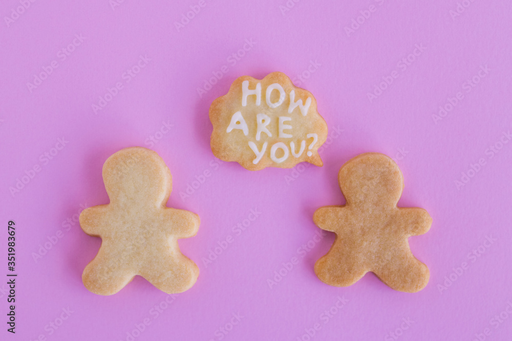 Homemade shortbread cookies with white glaze on pink background, top view. Two people with callout cloud with text ‘How are you?’ Homemade shortbread cookies with white glaze on pink background, top view. Two people with callout cloud with text ‘How are you?’