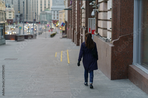 Moscow city center in spring sunset. Rare people. Woman walking to Lubyanka metro station. Back / rear view.  Coronavirus pandemic lifestyle. Concepts - stay home, save live.