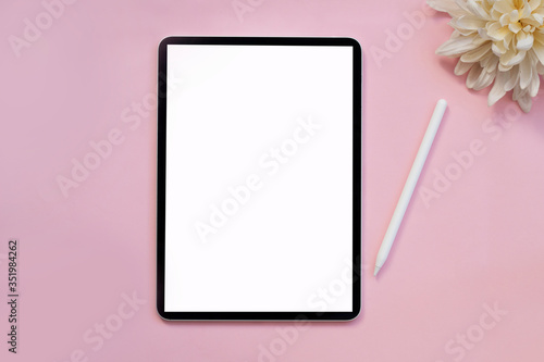 Modern tablet with pencil on a pink background.