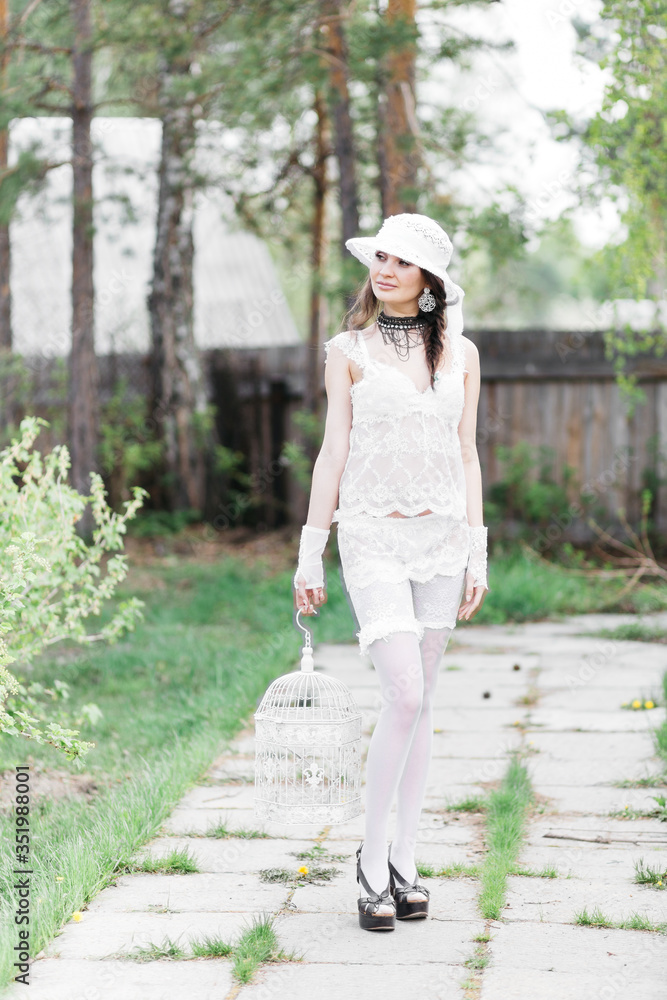 Tender girl in a white dress in the flowers of bird cherry