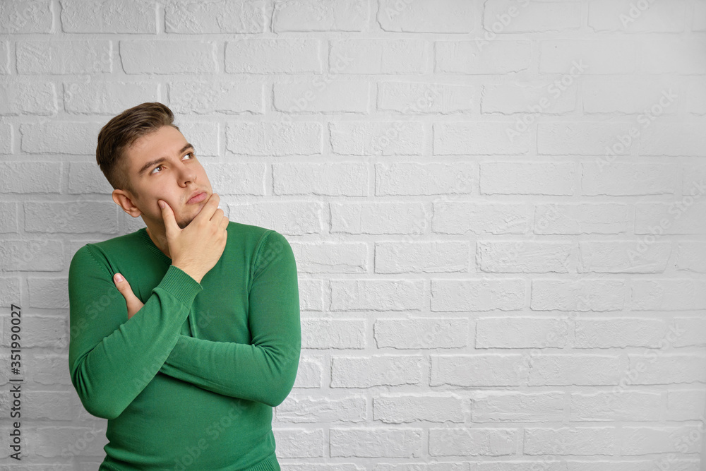 Portrait of a handsome caucasian man. Brick wall background. Studio photo. Thoughtful male thinking hard, looking away at copy space, leaning chin on hand. Brain work concept. Portrait of a handsome caucasian man. Brick wall background. Studio photo. Thoughtful male thinking hard, looking away at copy space, leaning chin on hand. Brain work concept.