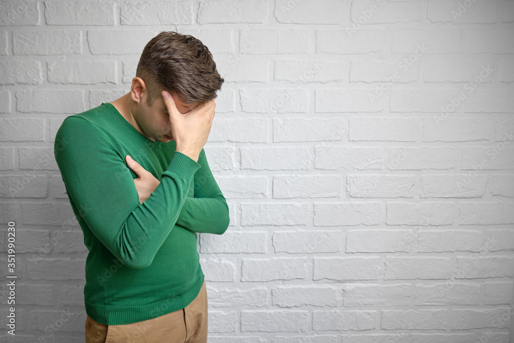 Portrait of young man with face palm gesture. Disappointed stressed out male making facepalm with hand. Brick wall background. Studio photo. There is a place to copy space. Portrait of young man with face palm gesture. Disappointed stressed out male making facepalm with hand. Brick wall background. Studio photo. There is a place to copy space.