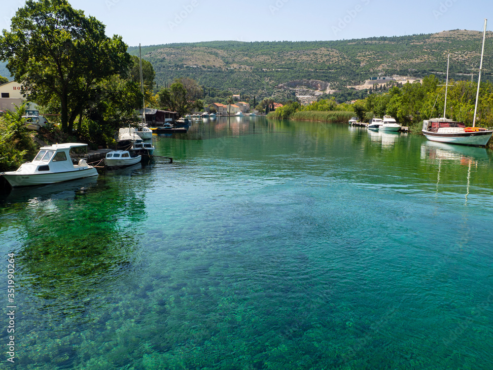 Barcos amarrados  en las aguas transparentes verdes de Croacia, con las montañas llenas de árboles verdes al fondo. Verano de 2019