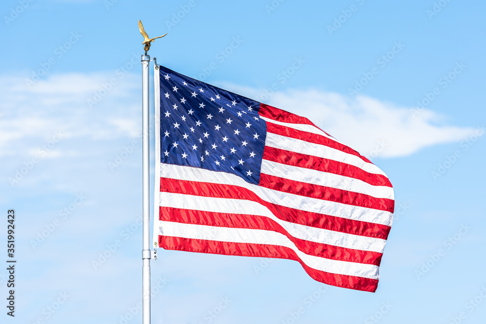 American flag is flowing in the wind on blue sky background.