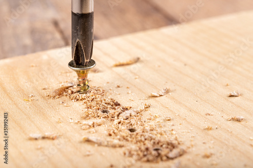 Screwing metal screws into chipboard for furniture construction. Small carpentry work in the home workshop.