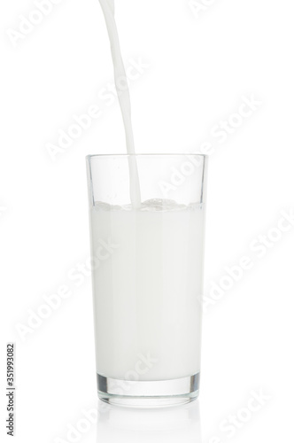 Pouring fresh milk in glass on white background