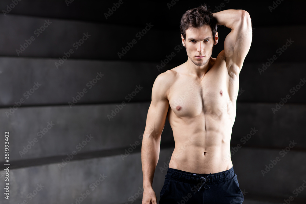 Handsome sport sexy stripped guy portrait on dark background.