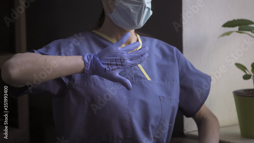 Doctor shows an open palm in disposable glove with the inscription HELP standing near the window. Close up shot. Medicine and healthcare concept