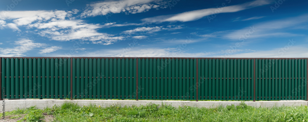Green metal fence. The sky with clouds. Green metal fence. The sky with clouds.
