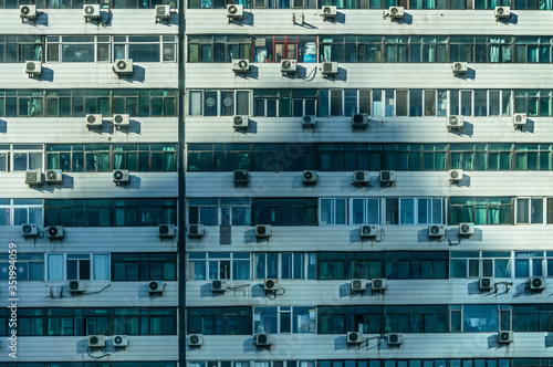 Wall of a block of flats, numerous air conditioners mounted outside the flat.