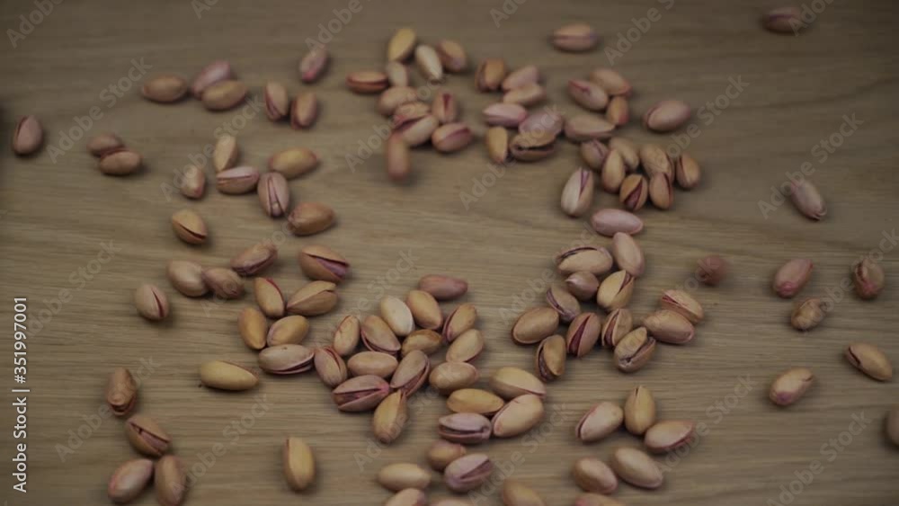 Organic pistachio falling on wooden background. Slow motion. Organic pistachio falling on wooden background. Slow motion.