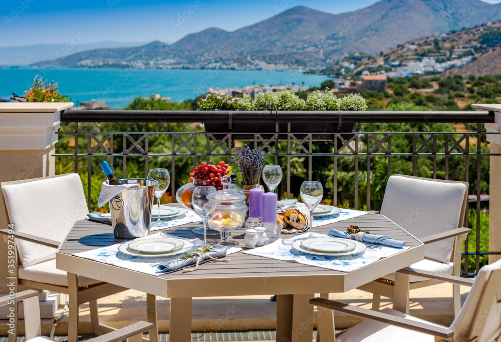 Table with fruits and wine on a summer terrace with sea and mountain views in Crete in Greece.
