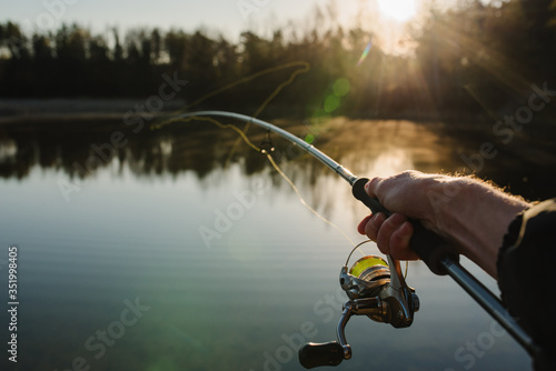Obraz na plátne Fisherman with rod, spinning reel on the river bank