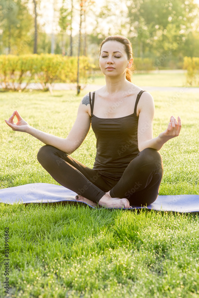 Young woman practicing yoga outdoors in the forest. Beautiful girl sits in a pose of a half lotus. Harmony and meditation concept. Healthy lifestyle. Young woman practicing yoga outdoors in the forest. Beautiful girl sits in a pose of a half lotus. Harmony and meditation concept. Healthy lifestyle.