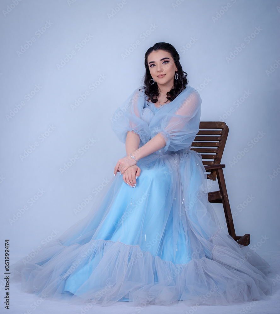Fototapeta premium young beautiful model in the image of princesse ,cinderella dressed in a blue dress,sitting on a chair