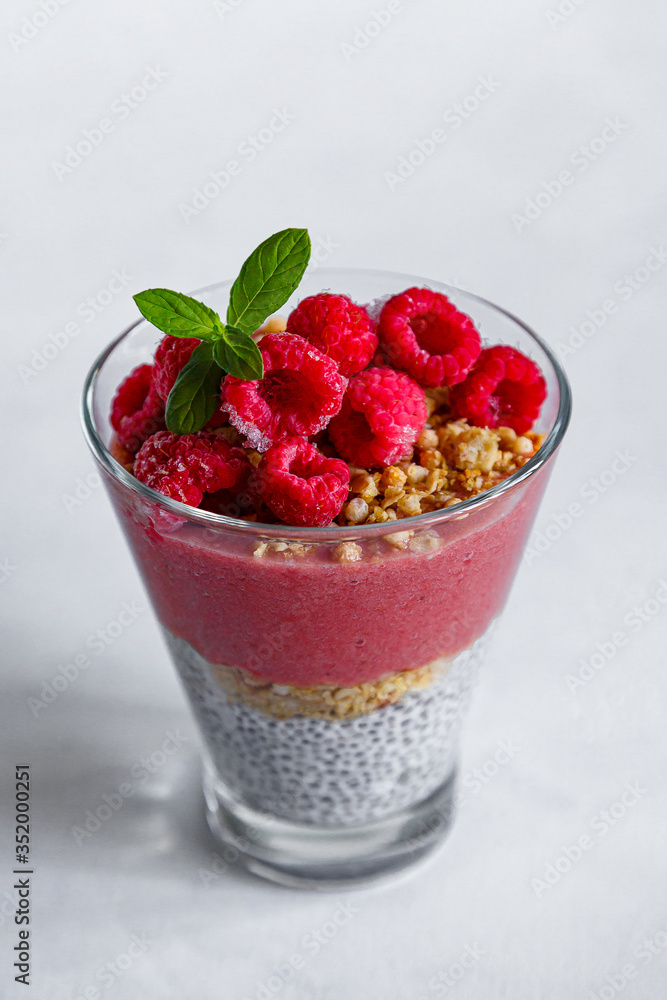 Fresh healthy dessert of Chia seeds raspberry puree banana and muesli in a glass Fresh healthy dessert of Chia seeds raspberry puree banana and muesli in a glass