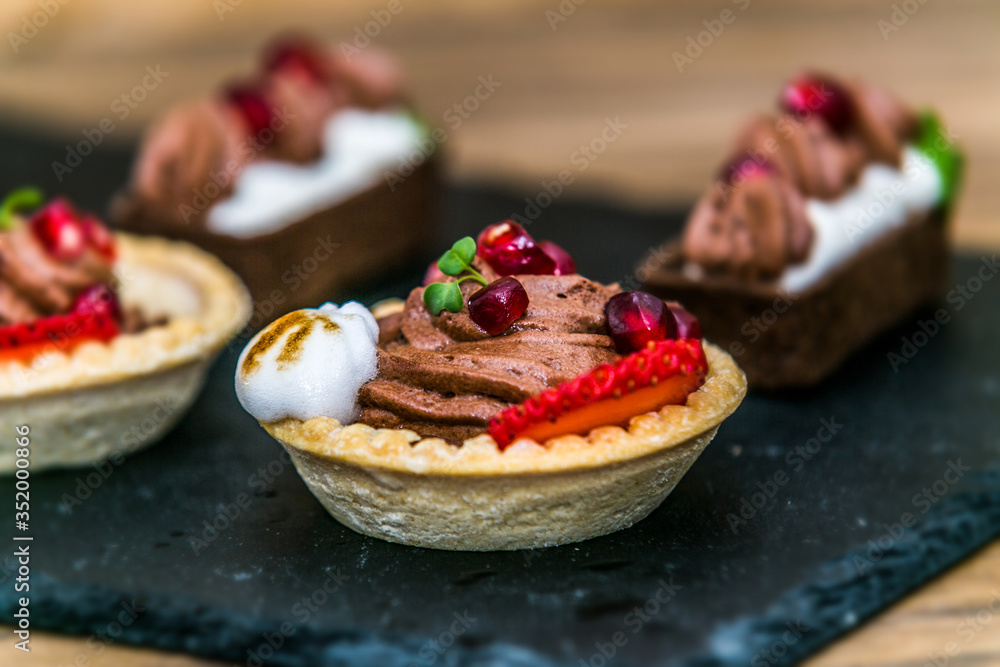 Sweet dessert Tartlets with different fresh fruit and delicious cream. Closeup Sweet dessert Tartlets with different fresh fruit and delicious cream. Closeup