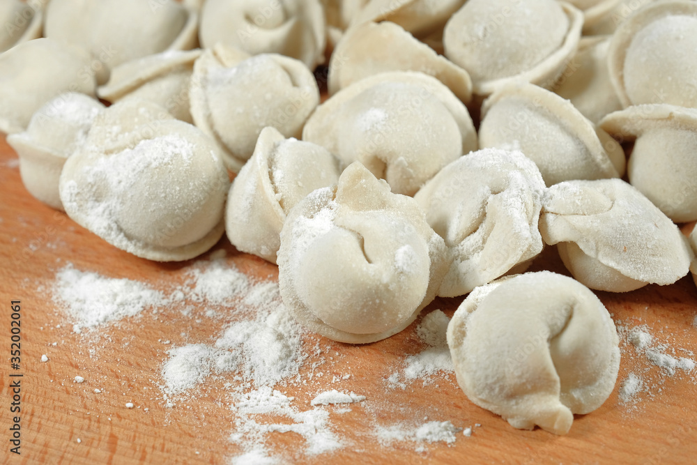 Raw dumplings on a wooden board, closeup. The process of making dumplings. Traditional homemade food. Raw dumplings on a wooden board, closeup. The process of making dumplings. Traditional homemade food.