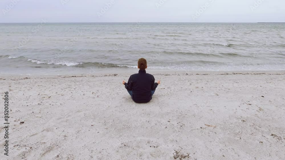 Young man sits alone in front of Baltic sea. Vallensbaek Strand, Denmark, Scandinavia at spring season Young man sits alone in front of Baltic sea. Vallensbaek Strand, Denmark, Scandinavia at spring season