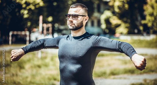 Young sportsman stretching and touching his hand outdoors. Young man stretching in the park.