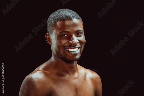 Nude afro american man with an excellent white-toothed smile looking at camera. Cut out on black background. Healthy teeth concept. Dental care concept. Toned image