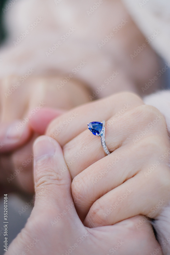 Two lovers are holding hands after proposal, engagement ring with blue sapphire