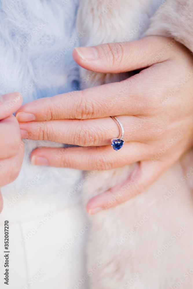 Fototapeta premium Close up of a woman's hand with blue sapphire engagement ring