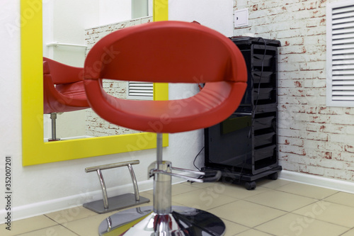 a chair in the barbershop opposite the mirror. chair of a pleasant shade. a chair for customers in a hair salon. Great mirror for customers. ordinary hairdresser
