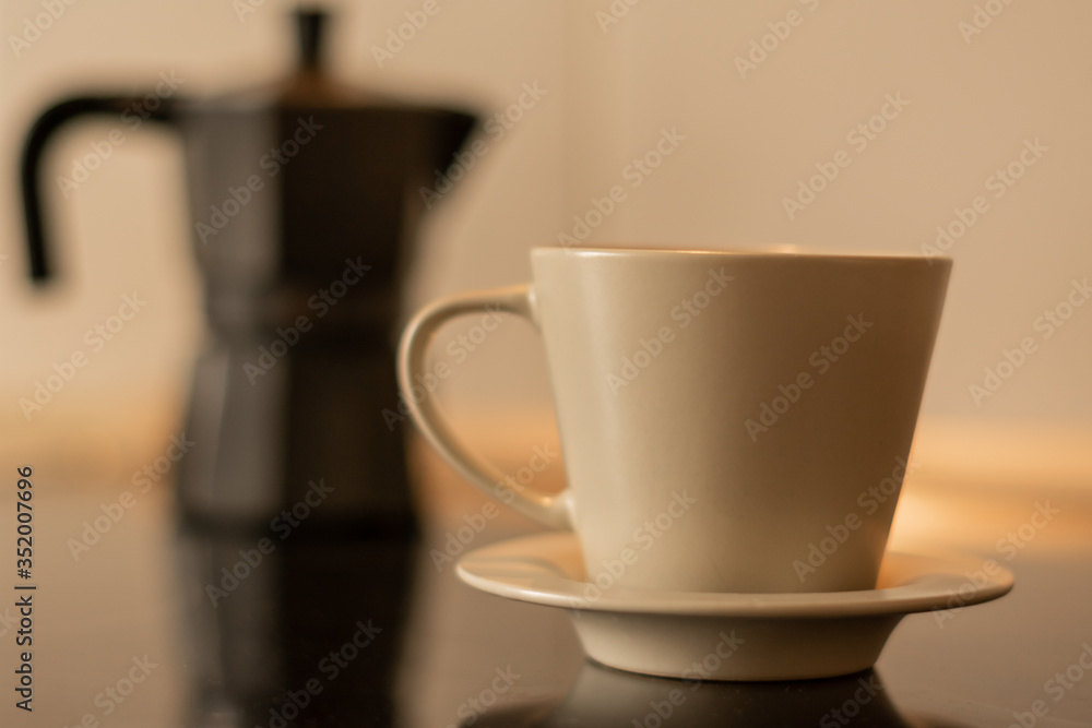 Coffee cup with a coffee maker in the background and out of focus Coffee cup with a coffee maker in the background and out of focus