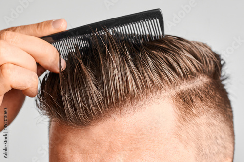 Foto Man combing his clean hair with plastic comb