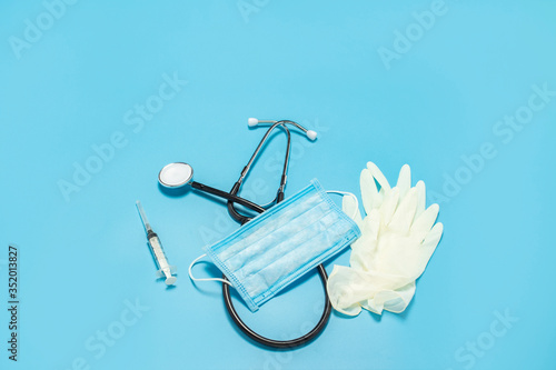 Medical stethoscope  latex gloves  syringe and protective mask on a blue background. Concept medicine  nurse  hospital  safety  epidemic. Banner. Flat lay  top view