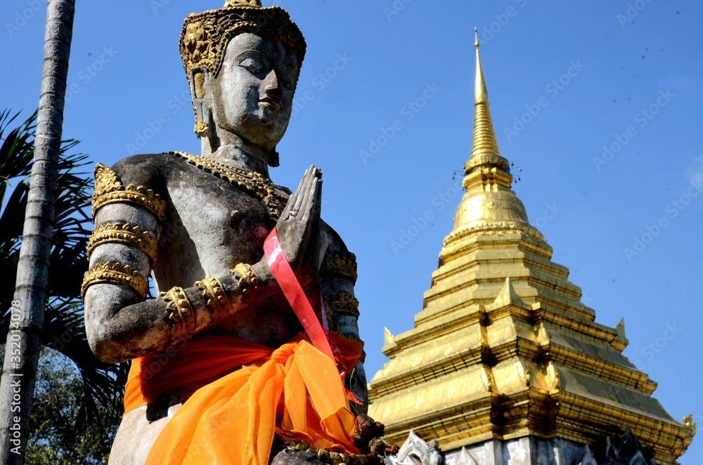 Black statue is standing next to the golden chedi of Wat Chiang Man in