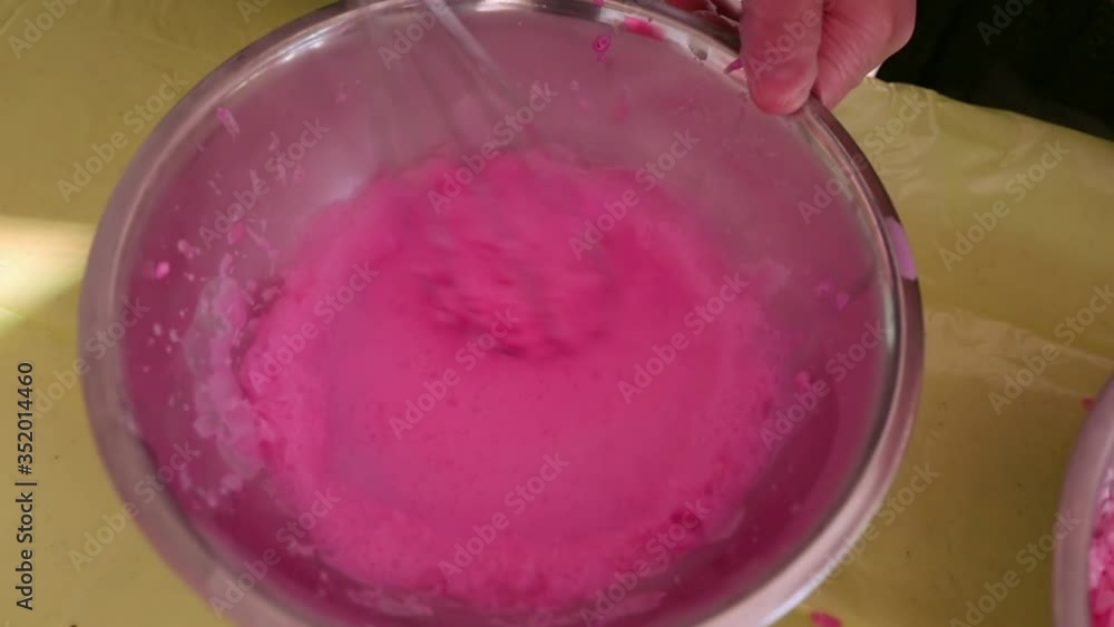 whisk stirs pink ice cream in a large silver dish whisk stirs pink ice cream in a large silver dish