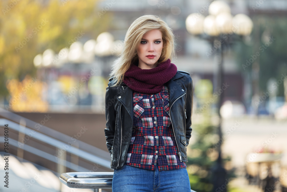 Young fashion blonde woman in black leather jacket and snood scarf