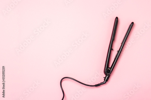 Hair straightener on a pink background. Concept of hair care, hairstyle, beauty salon, hairdresser. Flat lay, top view photo
