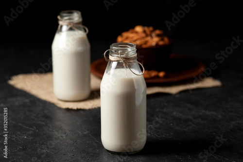 homemade almond milk in bottles with nuts on a black table  a variety of dairy products without sugar and lactose  a vegetarian drink